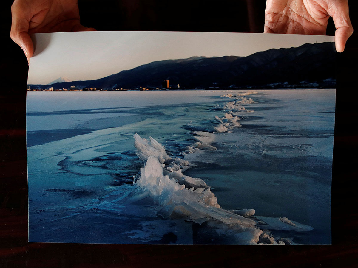 Shinto priest Kiyoshi Miyasaka displays a photo he took in 2006 that shows a phenomenon called omiwatari, or the crossing of the gods, which occurs when Lake Suwa freezes over and two sheets of ice collide. Photo: Reuters
