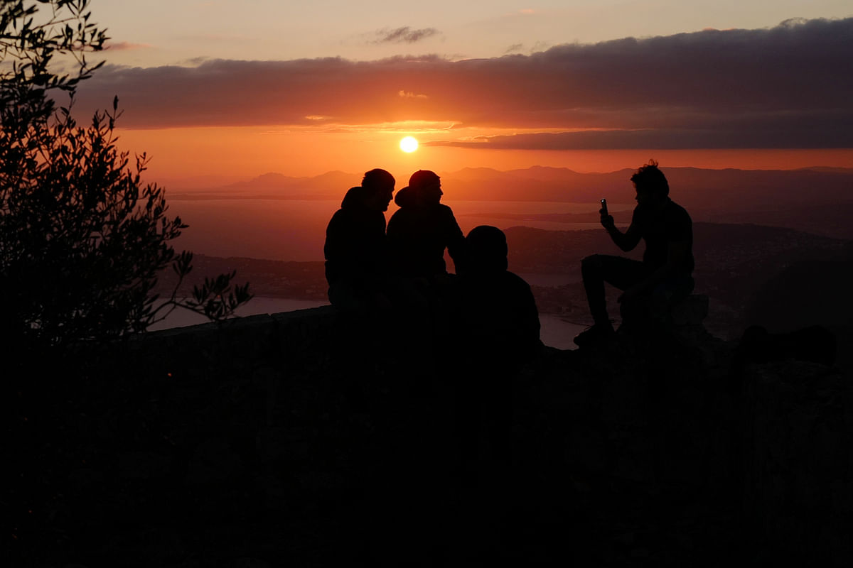 People look on during a sunset from the `Tete de chien` at La Turbie near Monaco, on 8 December 2019. Photo: AFP