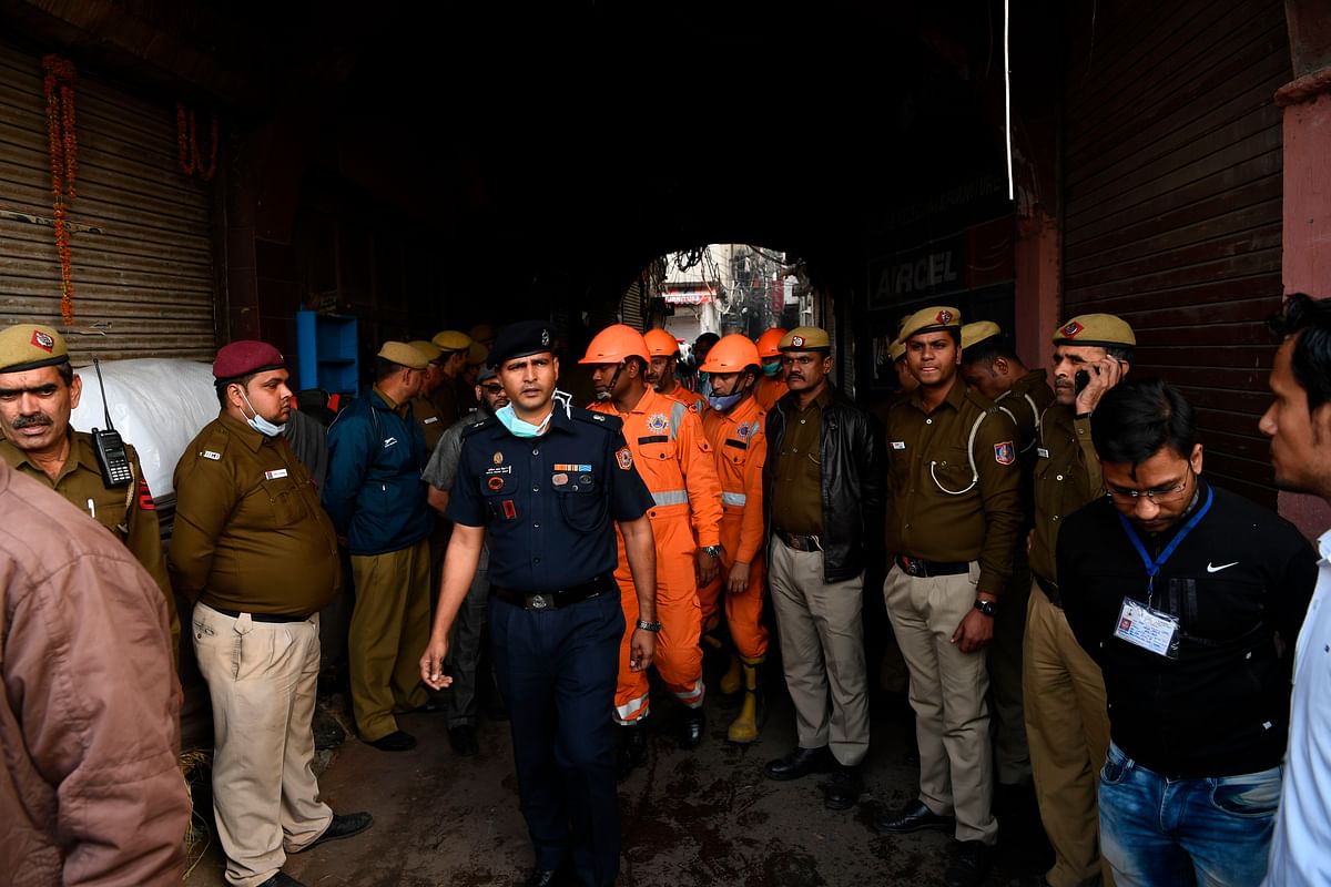 A National Disaster Response Froce (NDRF) team walk pass policemen blocking a street leading to a factory site where a fire broke out, in Anaj Mandi area of New Delhi on 8 December 2019. Photo: AFP