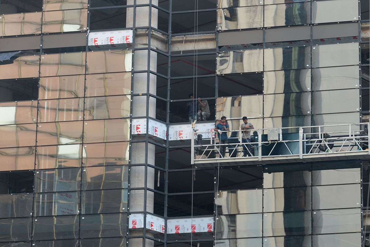 Workers install glass window onto a high rise building in Dhaka on 8 December 2019. Photo: AFP