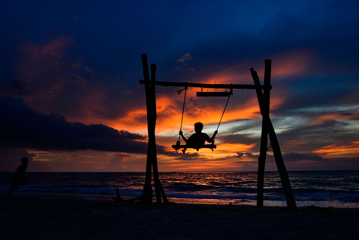 A child plays in a swing as the sun sets at Lhoknga beach in Aceh province on 9 December 2019. Photo: AFP