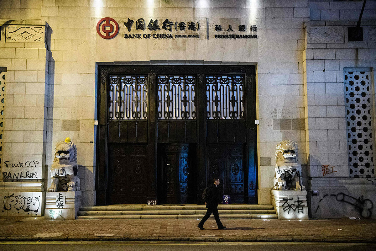 A man walks past graffiti left by protesters on the old Bank of China building following a pro-democracy rally from Victoria Park to Chater Road in Hong Kong on 8 December. Photo: AFP
