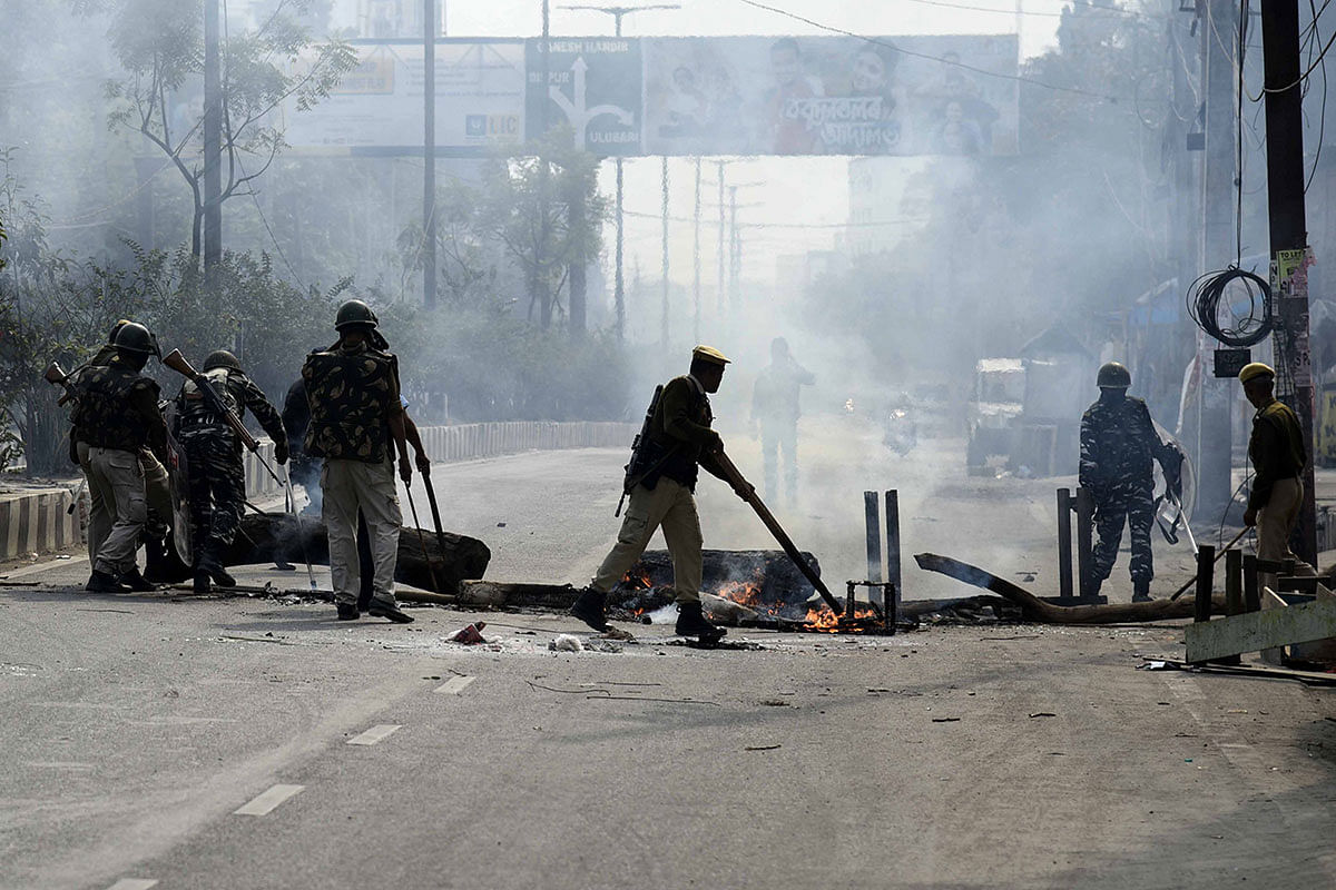 Police officers remove a burning blockade from a road in Guwahati on 12 December 2019. Photo: AFP