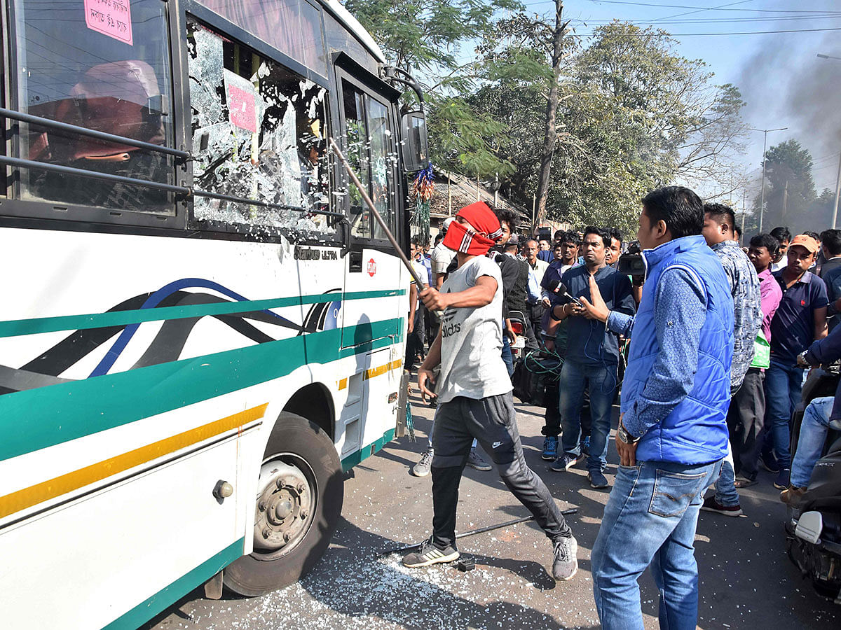 A protester breaks a glass window of a city bus during a strike called by All Assam Chutia Students` Union (AACSU) in protest against the government`s Citizenship Amendment Bill, in Guwahati on 9 December. Photo: AFP