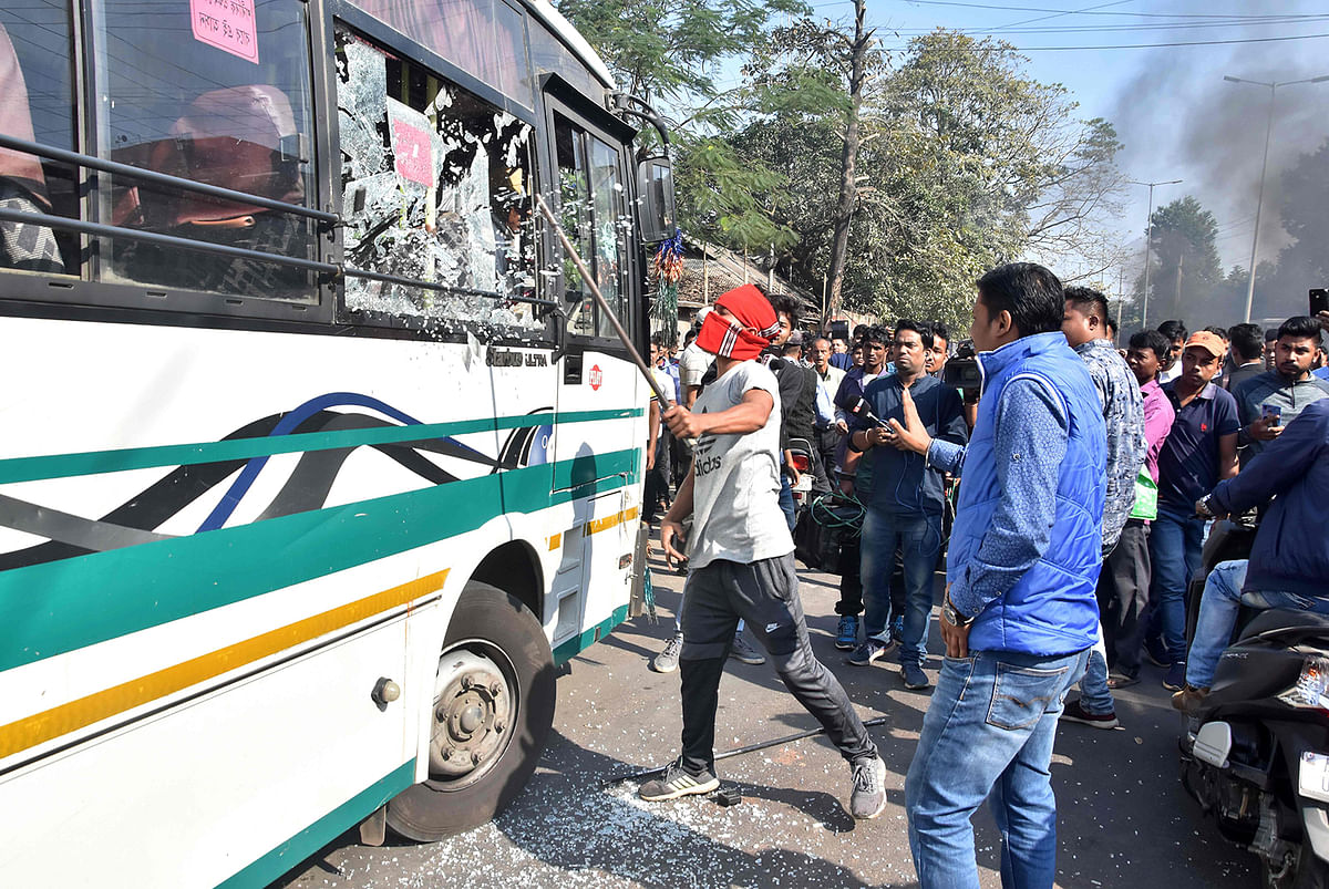 A protester breaks a glass window of a city bus during a strike called by All Assam Chutia Students` Union (AACSU) in protest against the government`s Citizenship Amendment Bill, in Guwahati on December 9, 2019. Photo: AFP