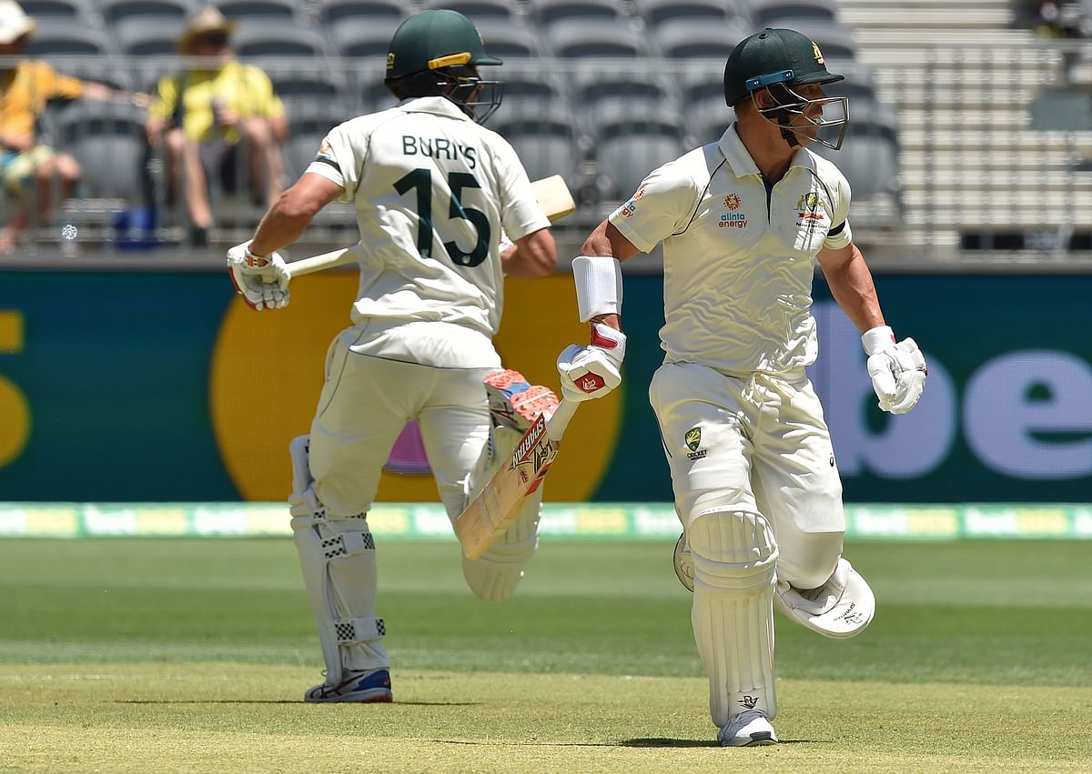 Australia`s David Warner (R) and Joe Burns (L) make runs against New Zealand on day one of the first Test cricket match between Australia and New Zealand at the Perth Stadium in Perth on 12 December 2019. Photo: AFP