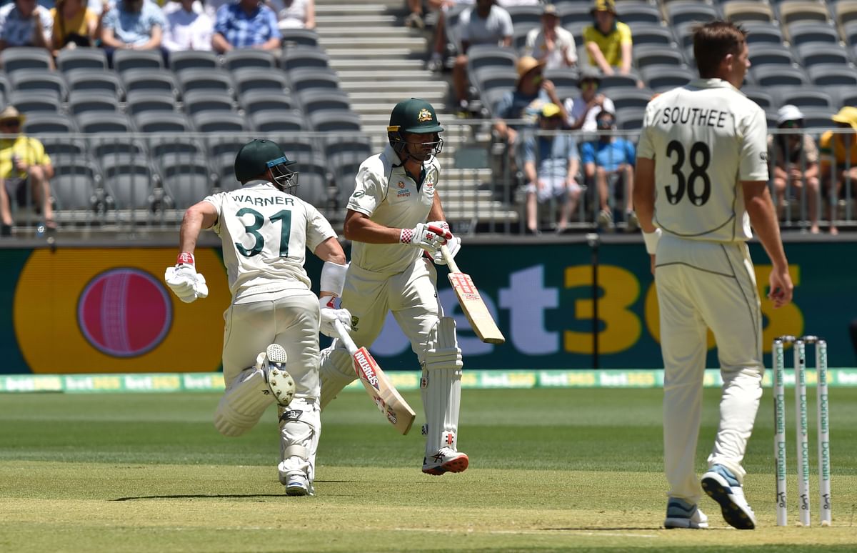 Australia`s David Warner (L) and Joe Burns (C) make runs as New Zealand bowler Tim Southee (R) looks on, on day one of the first Test cricket match between Australia and New Zealand at the Perth Stadium in Perth on 12 December 2019. Photo: AFP