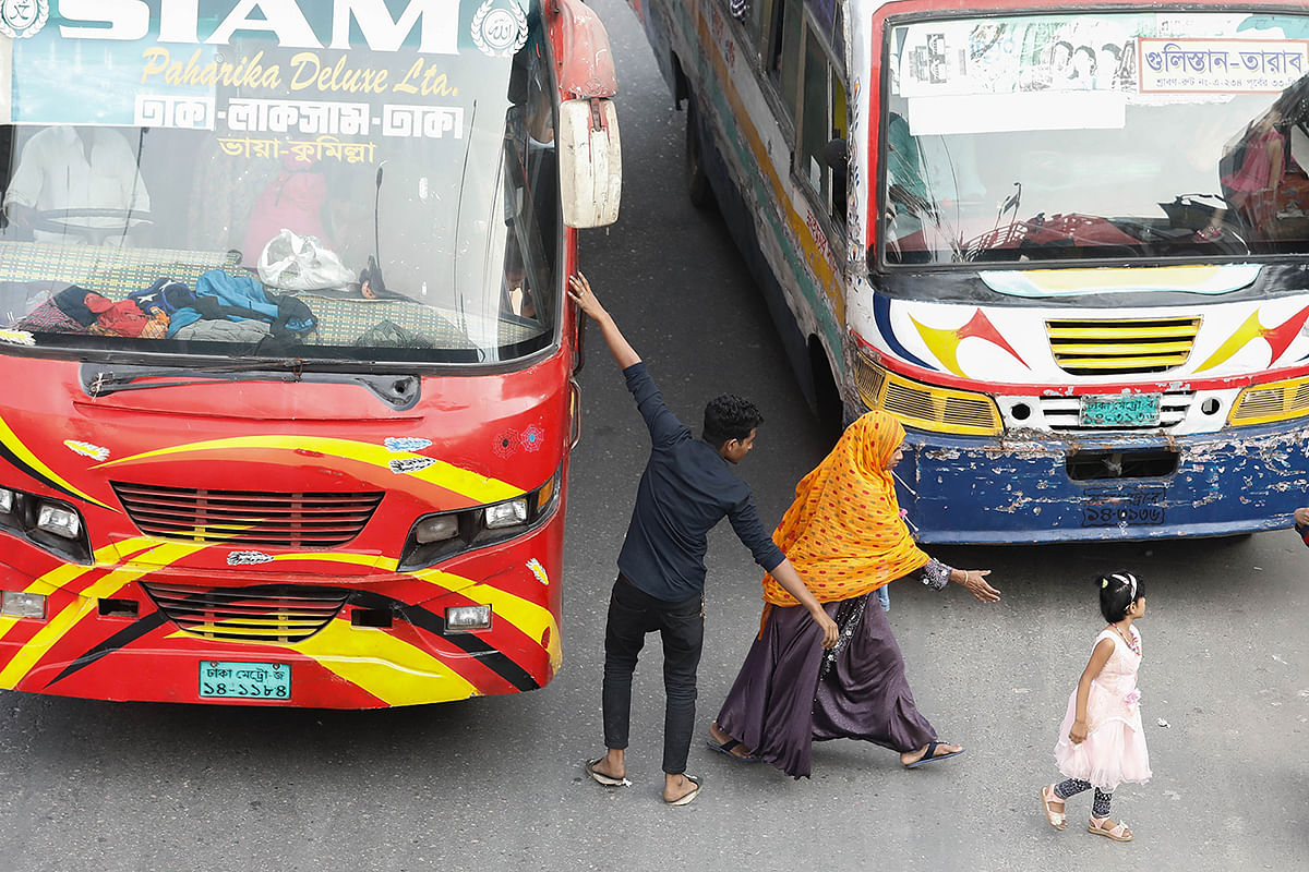 A woman passenger tries to save a child as they are dropped off by the bus conductor in the middle of a busy road at Dania, Dhaka on 10 December 2019. Photo: Dipu Malakar