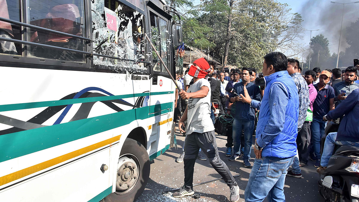 A protester breaks a glass window of a city bus during a strike called by All Assam Chutia Students` Union (AACSU) in protest against the government`s Citizenship Amendment Bill, in Guwahati on 9 December 2019. AFP File Photo