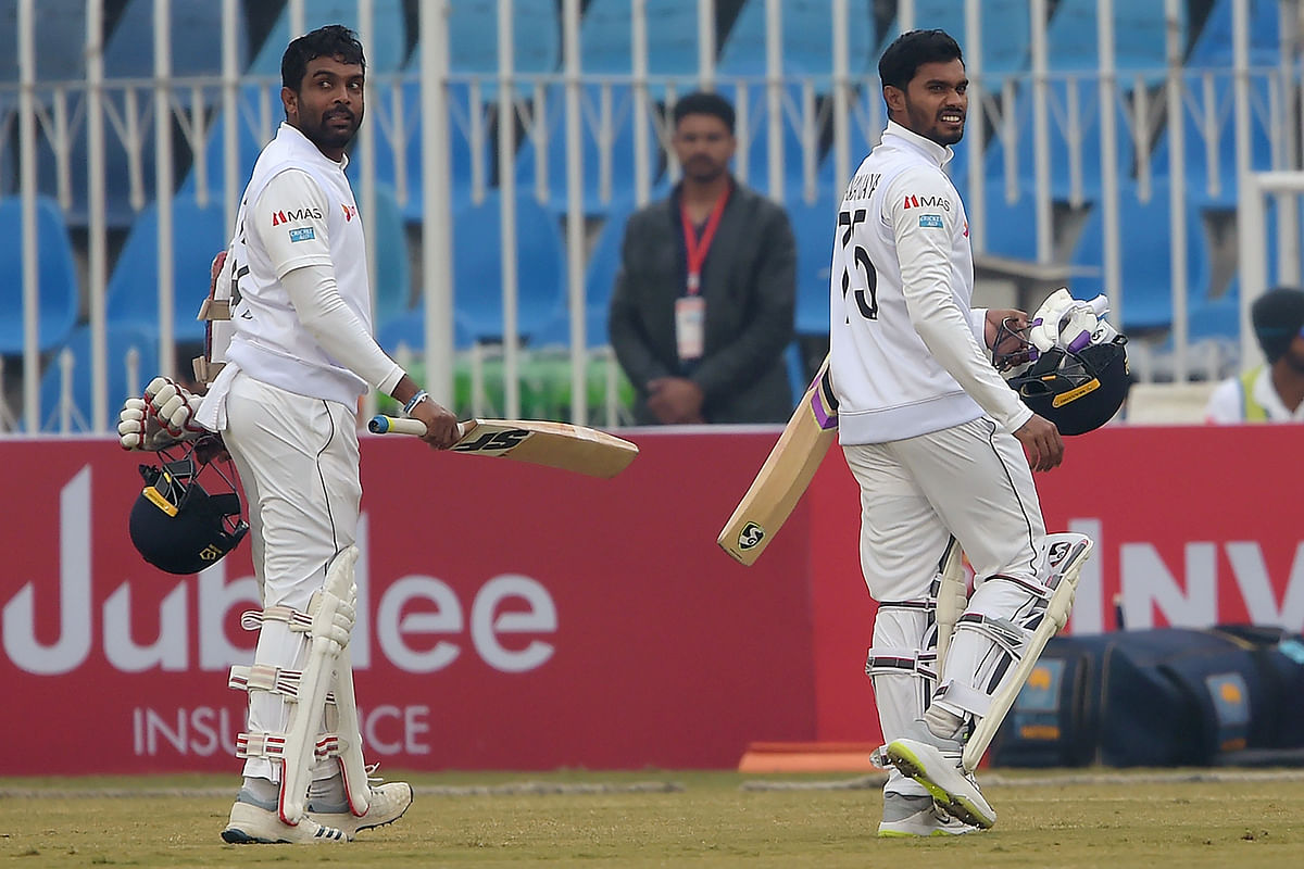 Sri Lanka`s Dhananjaya de Silva (R) and Dilruwan Perera walk back to the pavilion after the game was stopped due to bad light during the third day of the first Test cricket match between Pakistan and Sri Lanka at the Rawalpindi ricket Stadium in Rawalpindi on 13 December, 2019. Photo: AFP