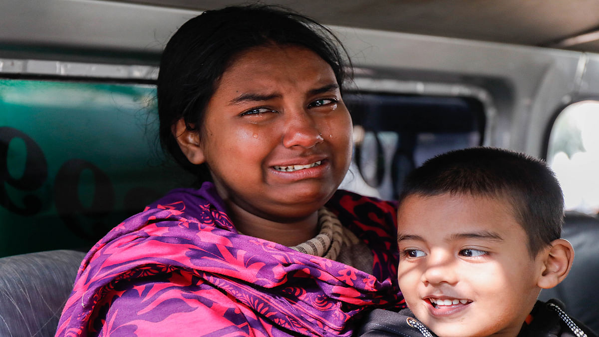 A woman with a child at Dhaka Medical College and Hospital on 13 December mourns her husband killed in the deadly plastic factory fire in Keraniganj, Dhaka on 12 December 2019. Photo : Dipu Malakar