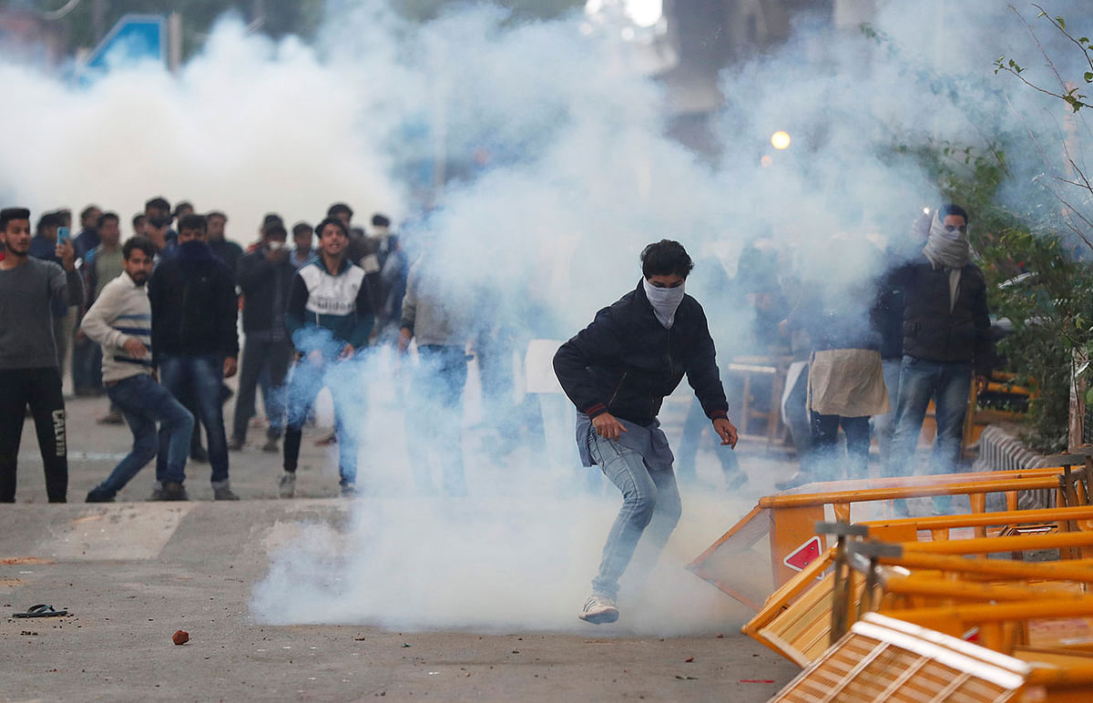 Protesters run for cover amid tear gas fired by police during a protest against the Citizenship Amendment Bill, a bill that seeks to give citizenship to religious minorities persecuted in neighbouring Muslim countries, outside the Jamia Millia Islamia University in New Delhi, India, on 13 December 2019. Reuters File Photo