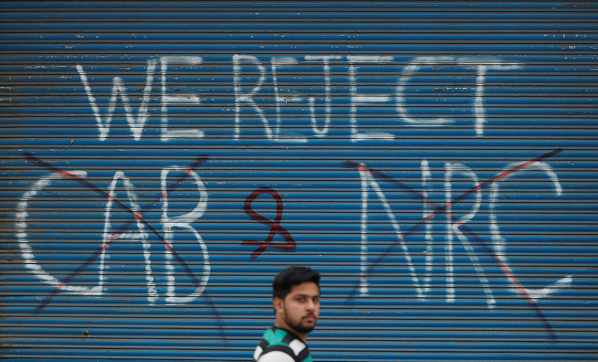 A man walks past a graffiti during a protest against a new citizenship law, from the roof tops of their homes, in Seelampur, area of Delhi, India on 17 December 2019. Photo: Reuters