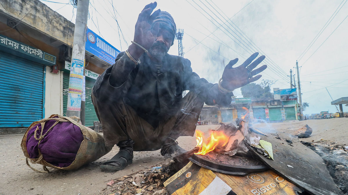 A man warms him up in bonfire amid cold wave in Launch Ghat area, Khulna on 19 December. Photo: Saddam Hossain