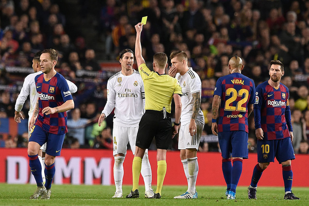 Real Madrid`s Spanish defender Sergio Ramos receives a yellow card by the referee during the `El Clasico` Spanish League football match at the Camp Nou Stadium in Barcelona on 18 December 2019. Photo: AFP