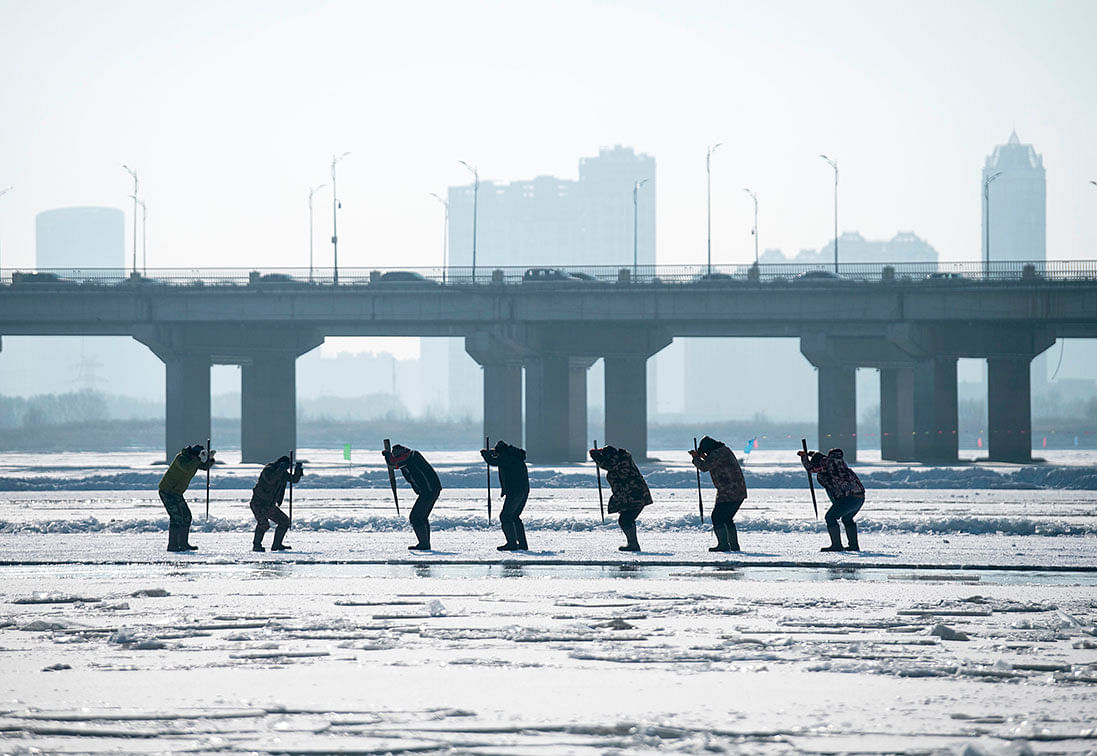 This photo taken on 12 December 2019 shows workers using picks to cut ice blocks from the frozen Songhua river in Harbin, China`s northeastern Heilongjiang province. Photo: AFP