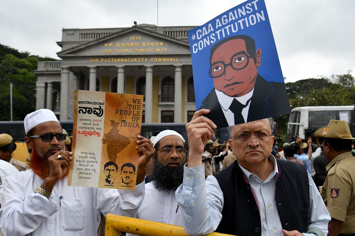 Historian Ramchandra Guha (R) holds a placard against India`s new citizenship law during protest held in spite of a curfew in Bangalore on 19 December 2019. Photo: AFP