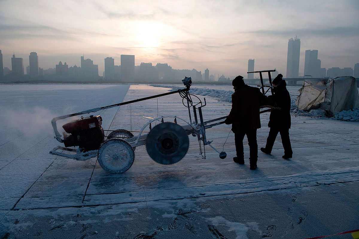This photo taken on 12 December 2019 shows workers using a machine to cut ice blocks from the frozen Songhua river in Harbin, China`s northeastern Heilongjiang province. Photo: AFP