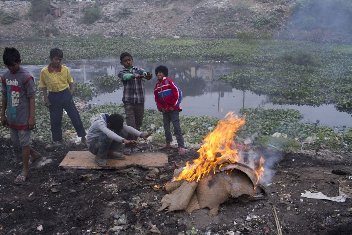 Children warm themselves around a bonfire on a cold day. Photo: UNB