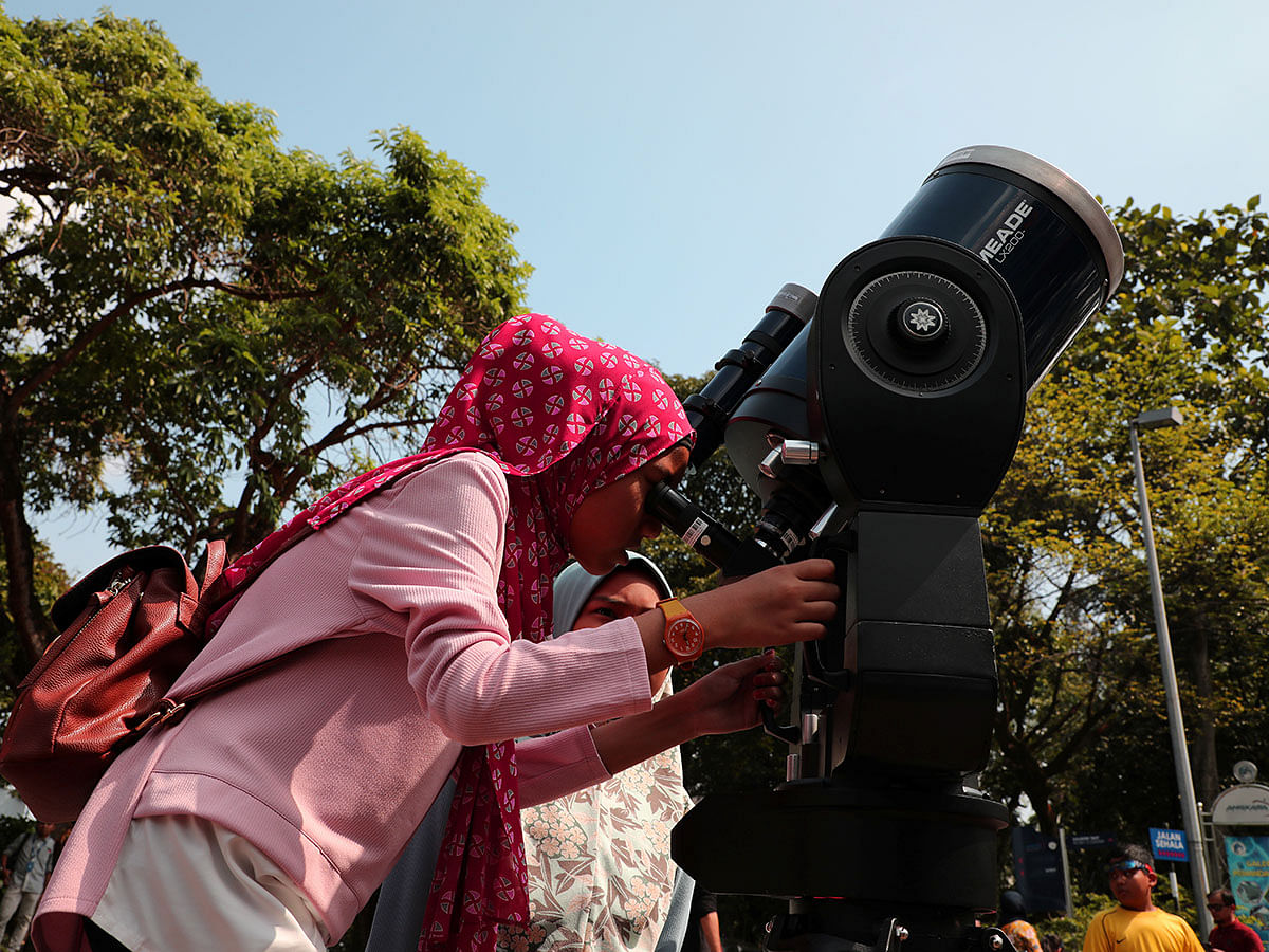 A girl looks at the sun through a telescope during the partial solar eclipse at the planetarium in Kuala Lumpur, Malaysia, on 26 December 2019. Photo: Reuters