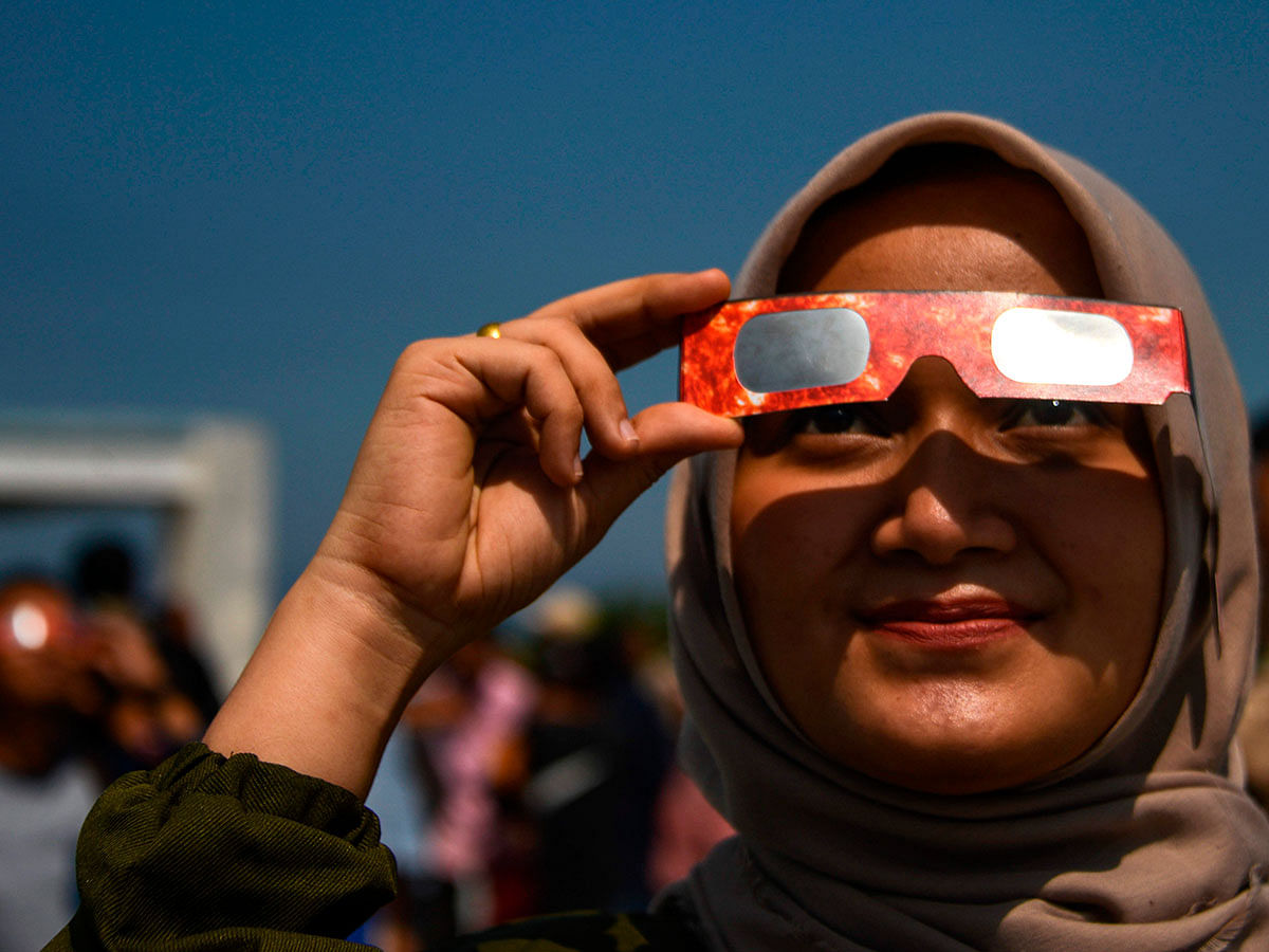People watch the moon move in front of the sun in a rare `ring of fire` solar eclipse in Banda Aceh on 26 December 2019. Photo: AFP