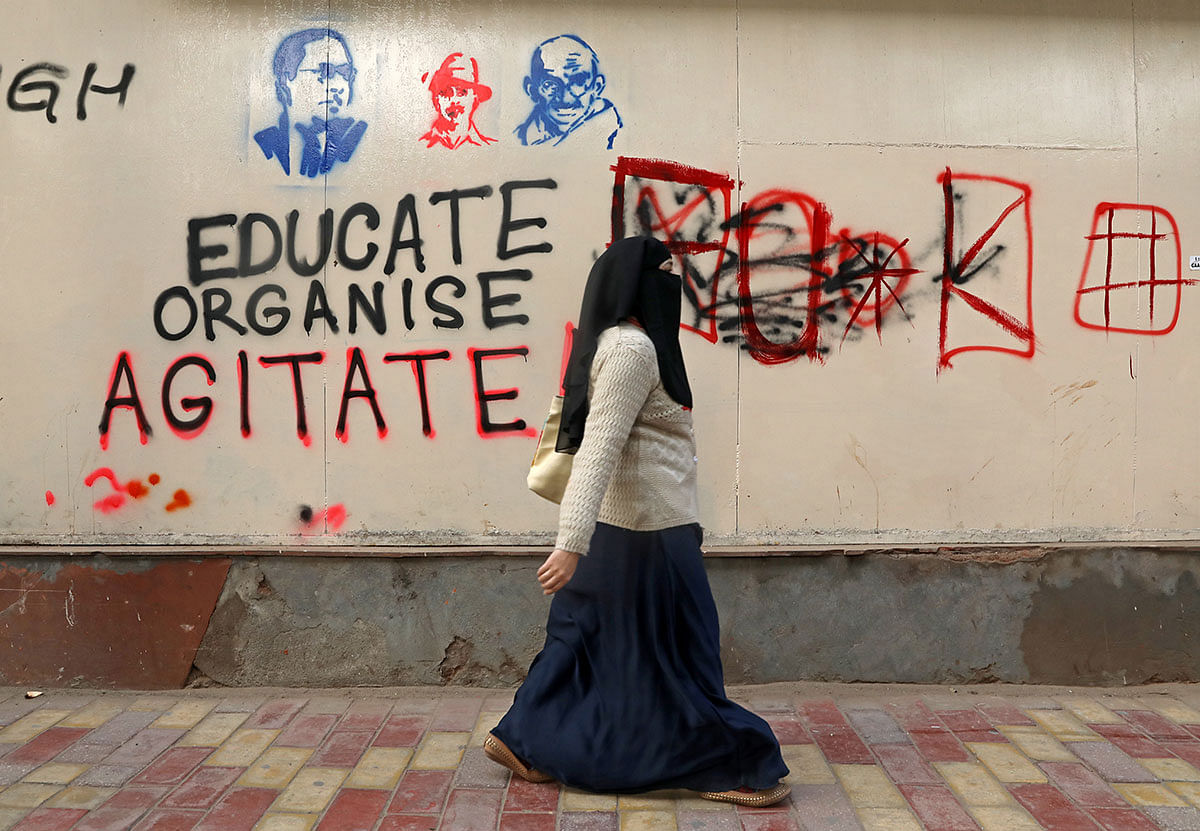A woman walks past a graffiti during a protest against a new citizenship law, outside the Jamia Millia Islamia university in New Delhi, India, on 26 December 2019. Photo: Reuters