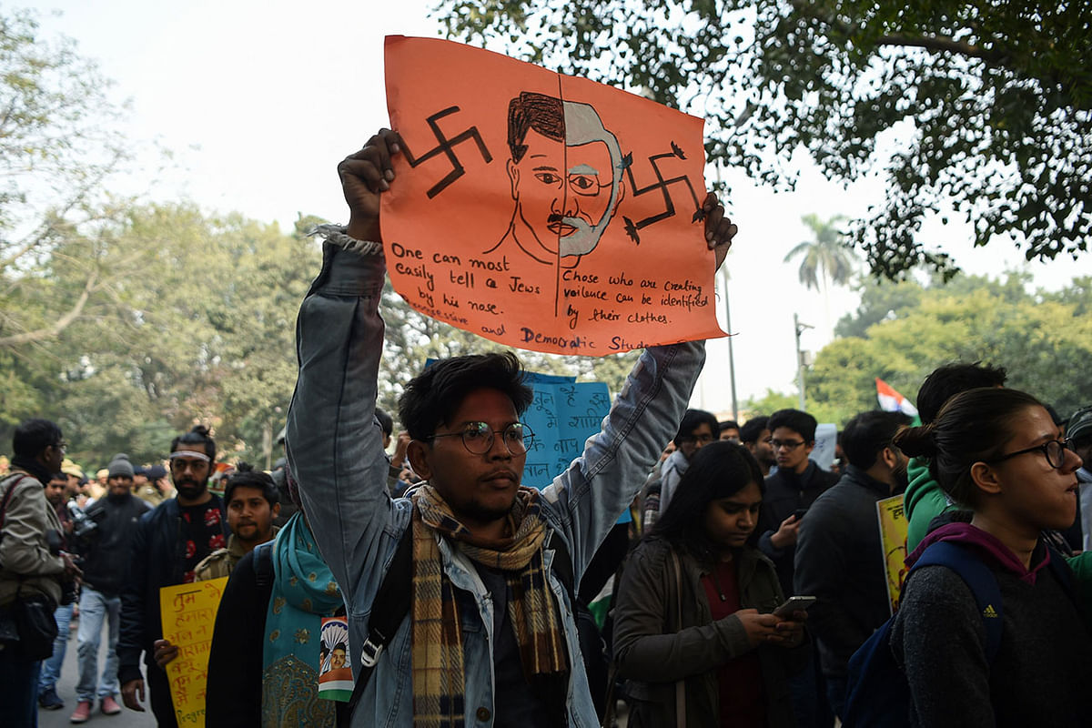 In this photo taken on 24 December 2019, a protester holds a placard comparing Indian prime minister Narendra Modi to German chancellor and Nazi Party leader Adolf Hitler at a demonstration against India`s new citizenship law in New Delhi. Photo: AFP