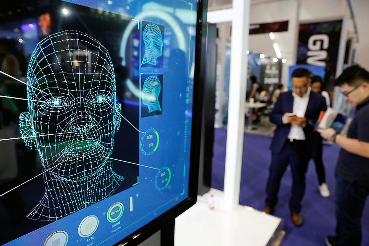 Visitors check their phones behind the screen advertising facial recognition software during Global Mobile Internet Conference (GMIC) at the National Convention in Beijing, China on 27 April 2018. Photo: Reuters