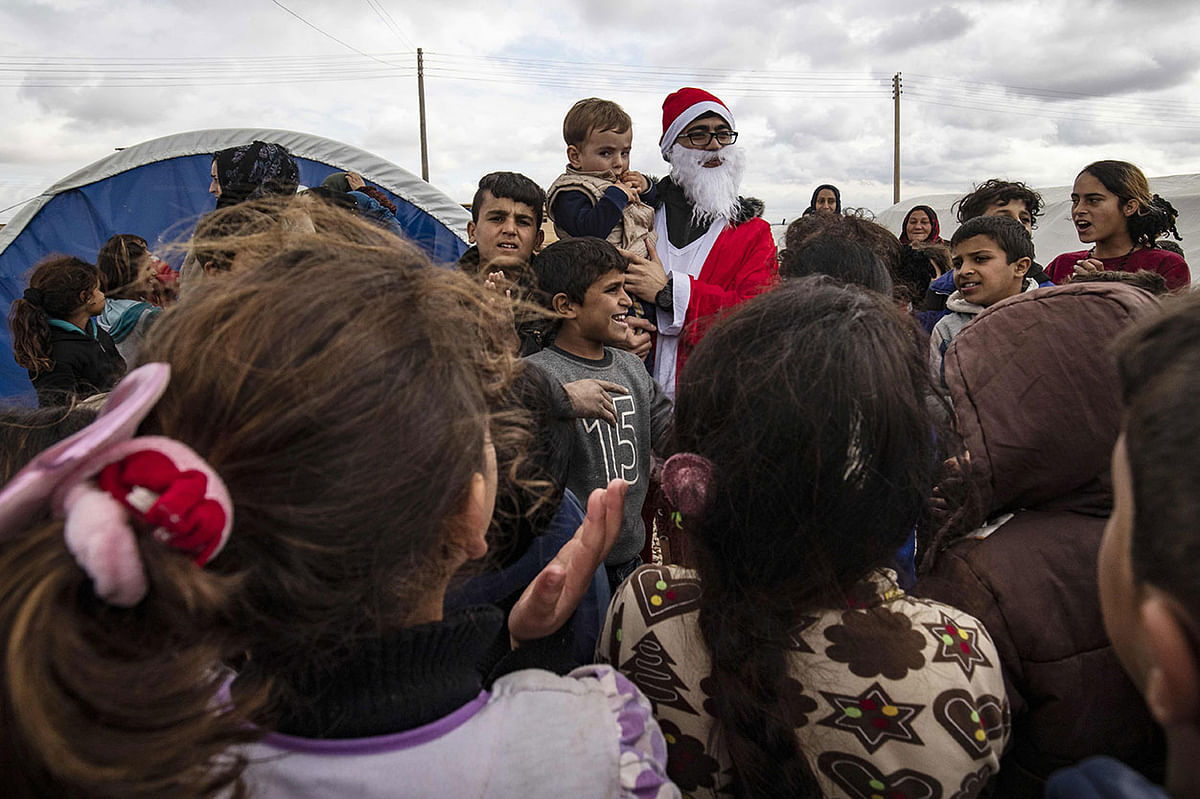 A man dressed as Father Christmas (Saint Nicholas or Santa Claus) visits displaced children from Ras al-Ain in a camp for internally displaced persons (IDP) in the mainly Kurdish northeastern Syrian province of Hasakeh on 27 December 2019. The gesture is part of the `We are with you` campaign organised by Kurdish Syrian youths living abroad who decided to send gifts to displaced children as a result of the eight-year-old conflict in Syria. Photo: AFP