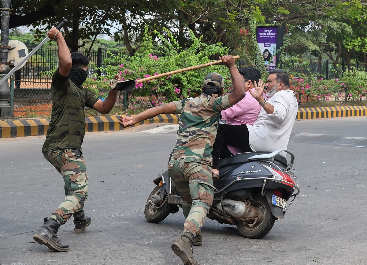 In this file picture taken on 20 December 2019, members of the Karnataka Reserve Police Force swing their sticks locally known as `lathi` to beat two men on a scooter who rode too close to a barricade set up on a street in Mangalore, amid heightened security due to protests over India’s new citizenship law. Photo: AFP