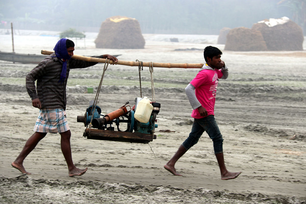 Farmers return with irrigation equipment from potato field after work at rural area in Rangpur recently. Photo: Moinul Islam