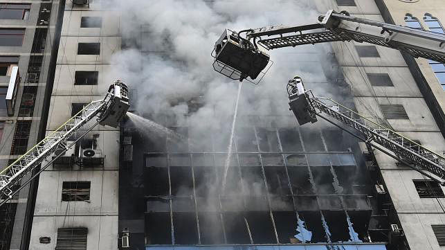 Firefighters on ladders work to extinguish a blaze in an office building in Dhaka on 28 March 2019. Photo: AFP