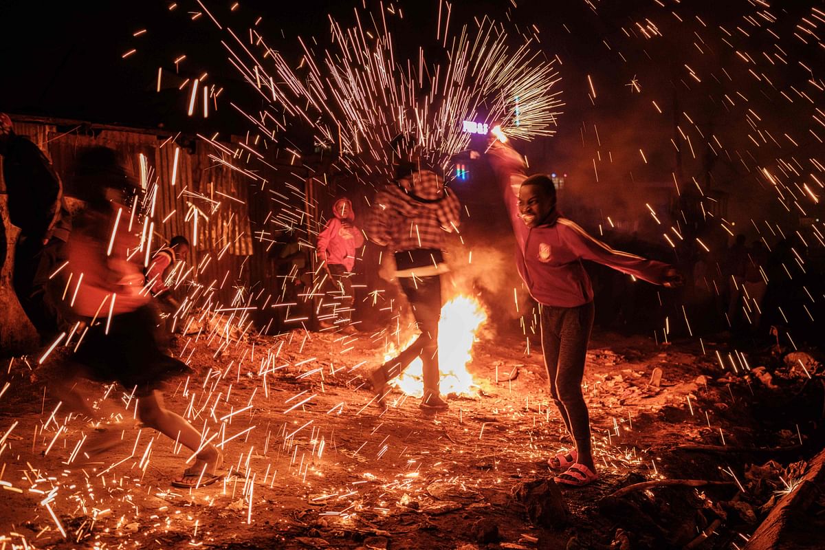 A girl spins a burning steelwool near a bonfire to sprinkle fire sparks as they celebrate the new year on a street of Kibera slum in Nairobi, on 1 January 2020. Photo: AFP