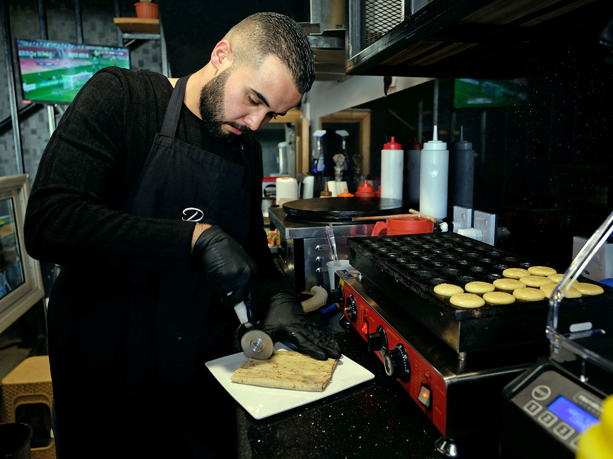 Belghasem Abdulsalam, 22, an oil engineering graduate, works at a cafe after baking courses for cakes and sweets at Sarah Center for Sweets, in Benghazi, Libya on 18 December 2019. Photo: Reuters