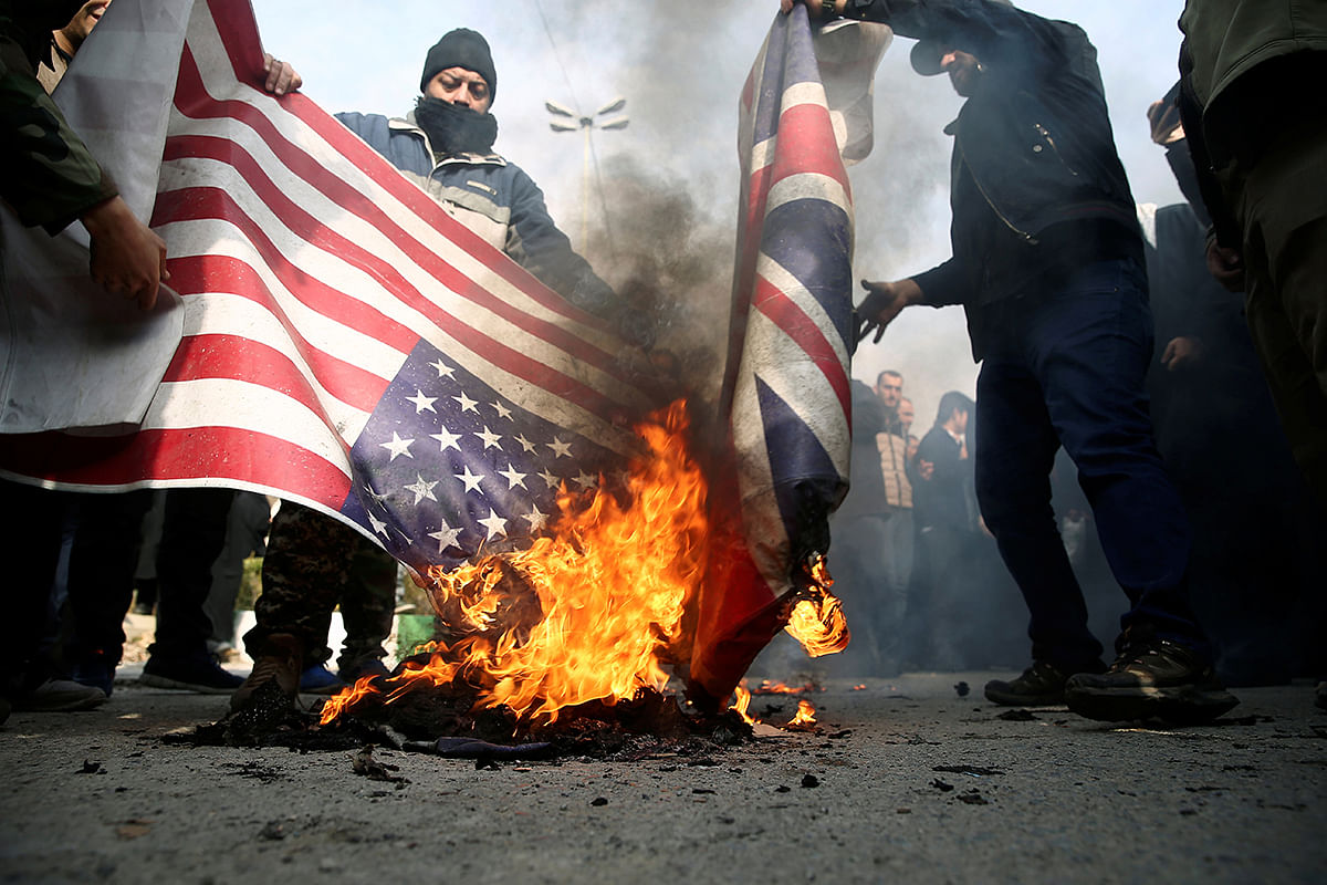 Demonstrators burn the US and British flags during a protest against the assassination of the Iranian major-general Qassem Soleimani, head of the elite Quds Force, and Iraqi militia commander Abu Mahdi al-Muhandis who were killed in an air strike in Baghdad airport, in Tehran, Iran on 3 January 2020. Photo: Reuters