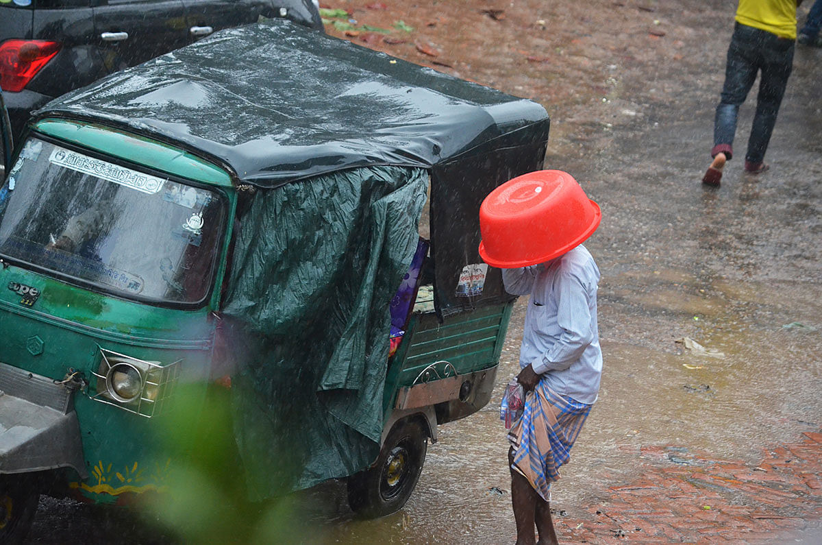 A man covering his head with a plastic bowl rides an auto-rickshaw in a drizzle at Dighinala, Khagrachhari on 3 January 2019. Photo: Palash Barua