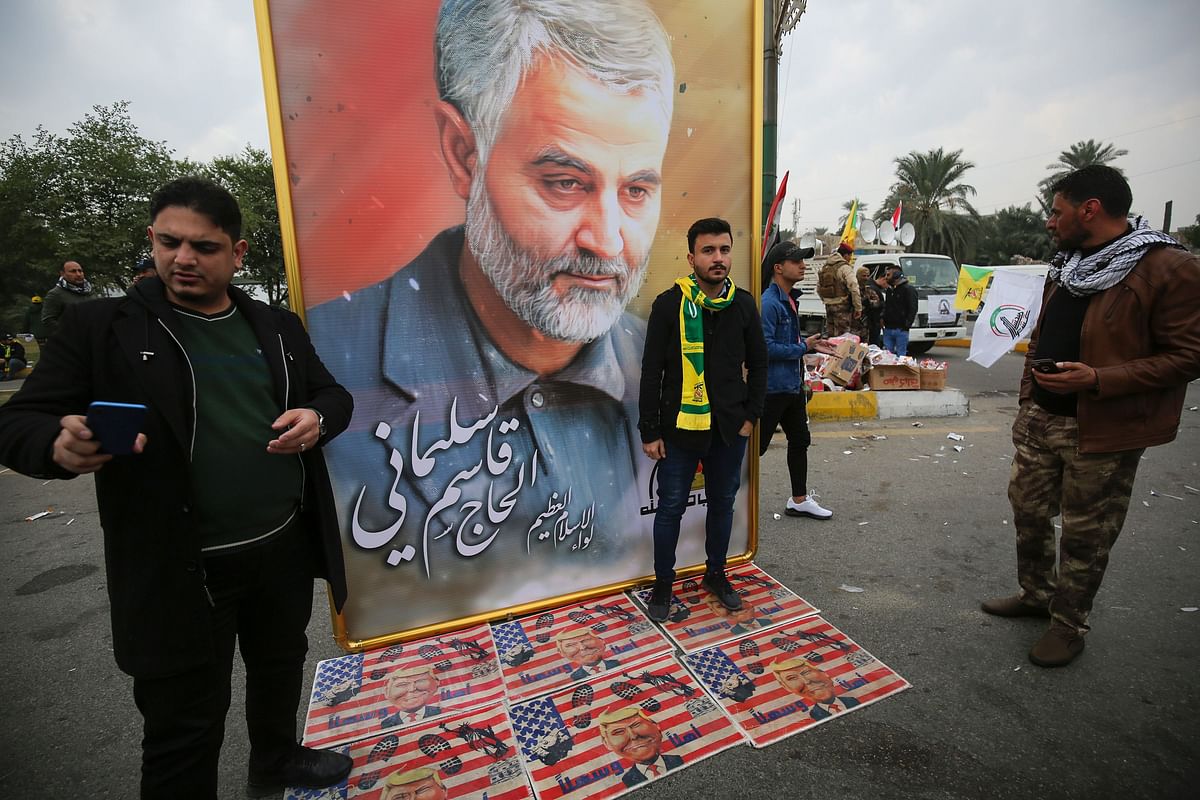 Supporters of the Hashed al-Shaabi paramilitary force and Iraq`s Hezbollah brigades pose for a picture next to a poster of Iranian military commander Qasem Soleimani (portrait) during a funeral, for Soleimani and Iraqi paramilitary chief Abu Mahdi al-Muhandis killed in a US air strike, in Baghdad`s district of al-Jadriya, in Baghdad`s high-security Green Zone, on 4 January, 2020. Photo: AFP