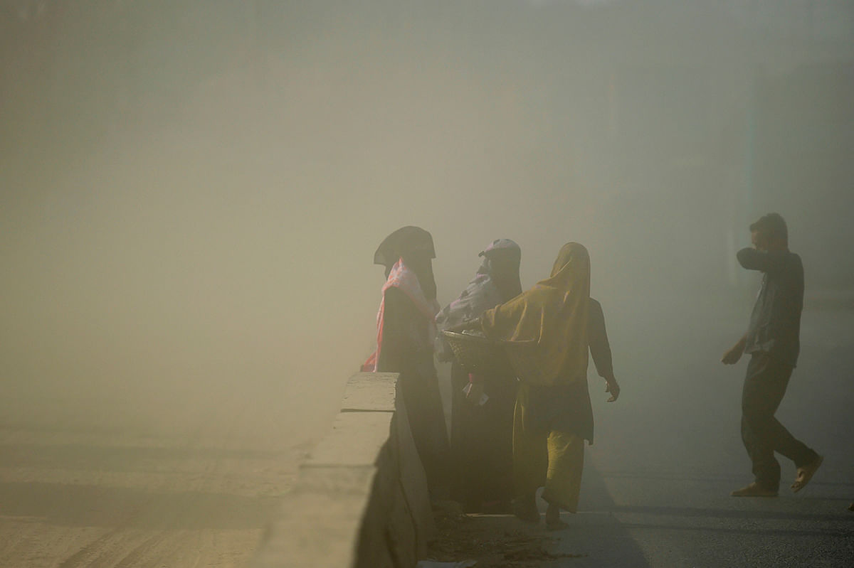 Bangladeshi commuters makes their way along a road under dusty conditions in Dhaka on 1 January, 2020. Photo: AFP