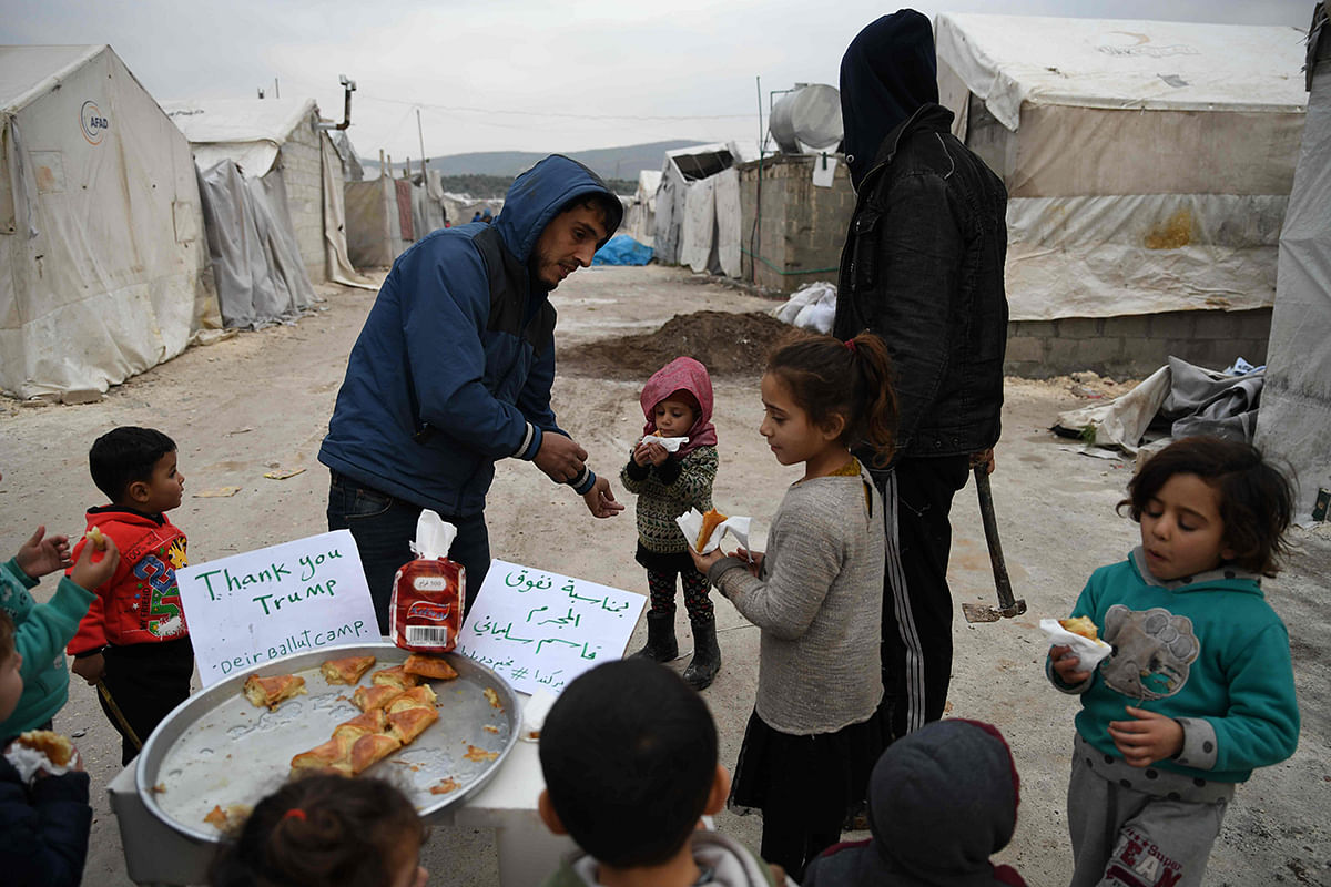 A Syrian man offers sweets to children to mark the killing on 3 January, 2020 of Qasem Soleimani, a top Revolutionary Guards commander in Iran, seen by the rebels as a main supporter of the Syrian regime which they have been fighting since 2011, at a camp for internally displaced Syrians near Dayr Ballut, in the rebel-held Aleppo province in the country`s northwest. Photo: AFP
