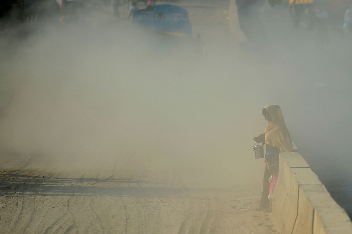 A Bangladeshi woman makes her way along a road under dusty conditions in Dhaka on 1 January, 2020. Photo: AFP