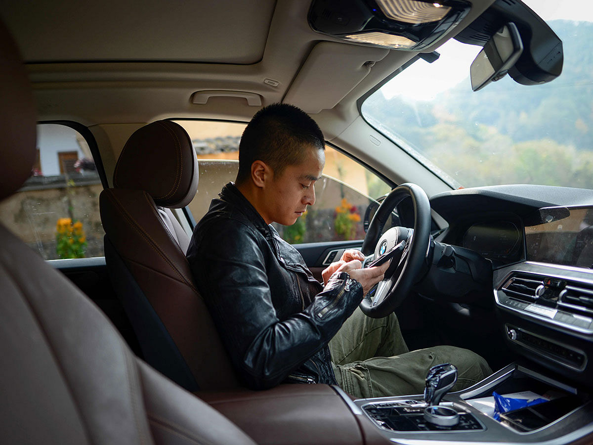 This picture taken on 13 November 2019 shows Chinese farmer Ma Gongzuo looking at his mobile phone in his car before driving to his apiary in Songyang county in China`s Zhejiang province. Photo: AFP