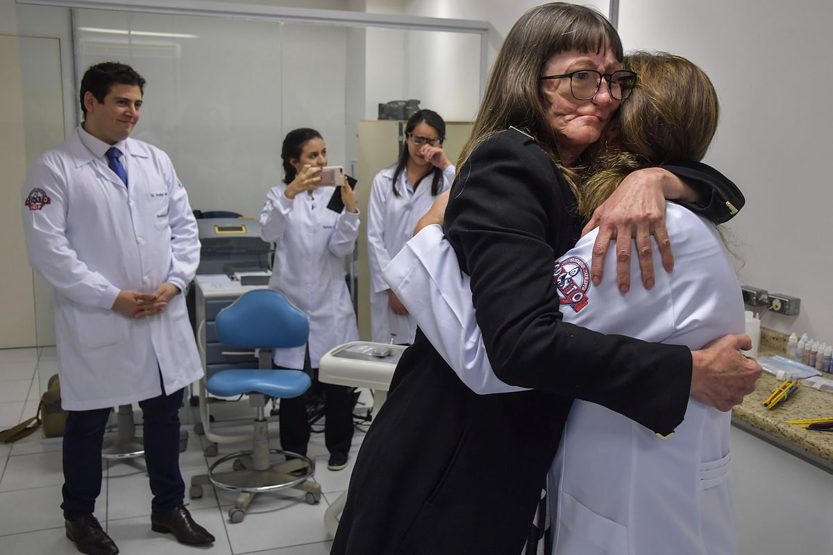 Denise Vicentin (2-R), who lost her right eye and part of her jaw to cancer, embraces a member of the medical staff of doctor Rodrigo Salazar-Gamarra (L) after receiving a digitally-engineered prosthesis, in Sao Paulo, Brazil, on 3 December 2019. Photo: AFP