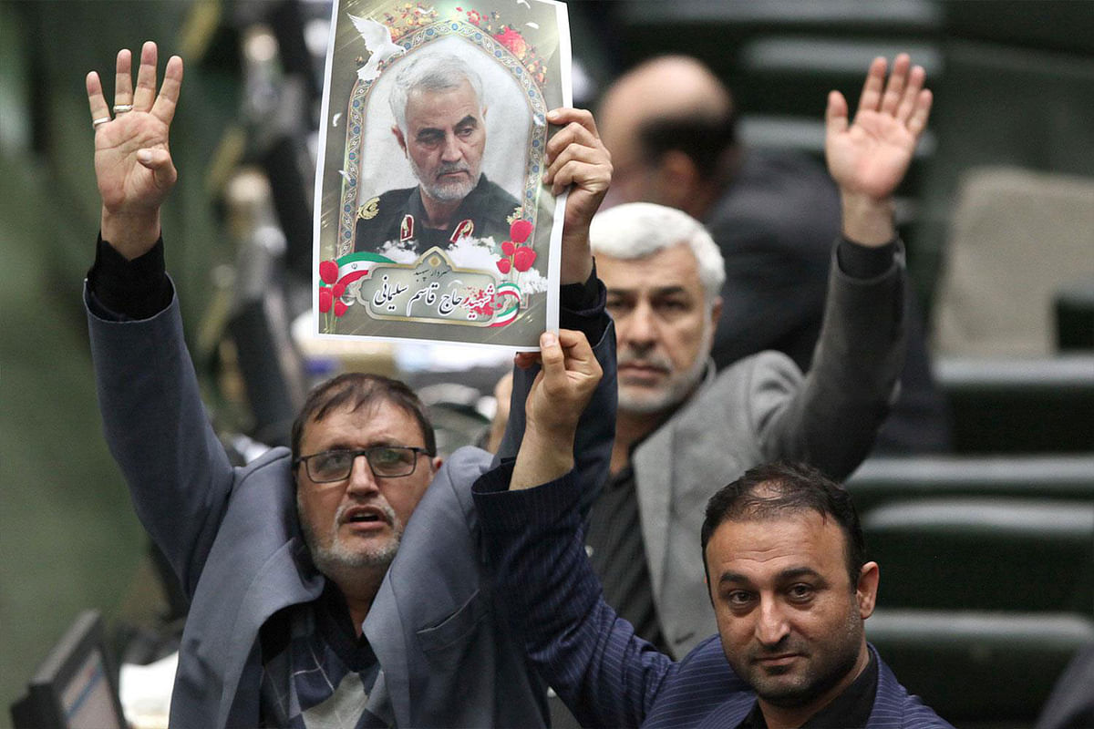 This handout picture provided by the Islamic Consultative Assembly News Agency (ICANA) on 7 January 2020 shows Iranian lawmakers holding pictures of slain top general Qasem Soleimani as they vote during a parliamentary session in Tehran. Photo: AFP
