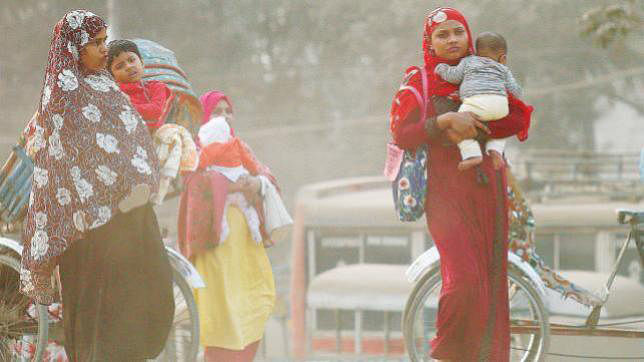 Women carrying children walk along a road in a cloud of dust at Postogola, Dhaka. Prothom Alo file photo