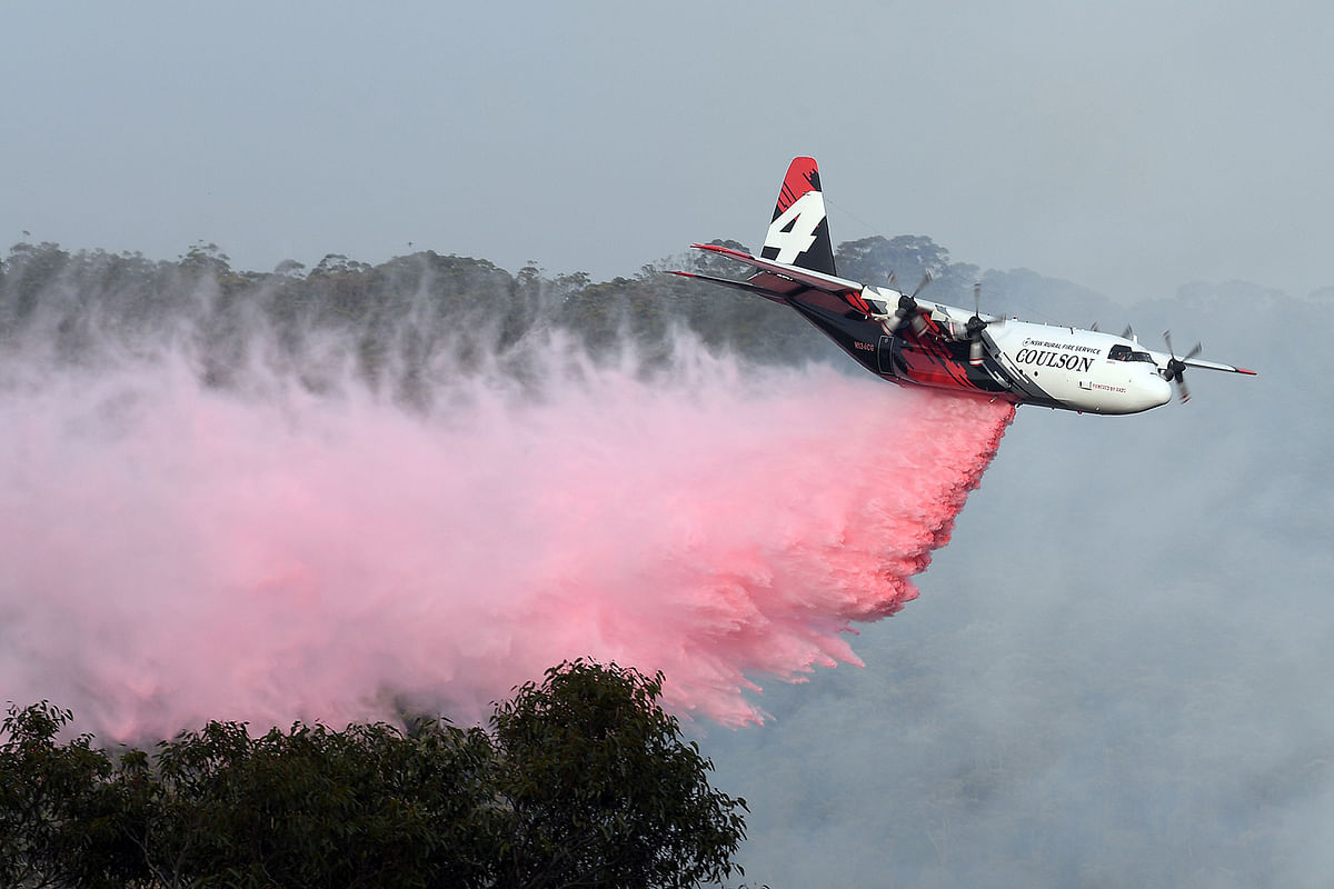 A plane drops fire retardent to protect a property during an operation to douse bushfires in Penrose, in Australia`s New South Wales state on 10 January 2020. Photo: AFP