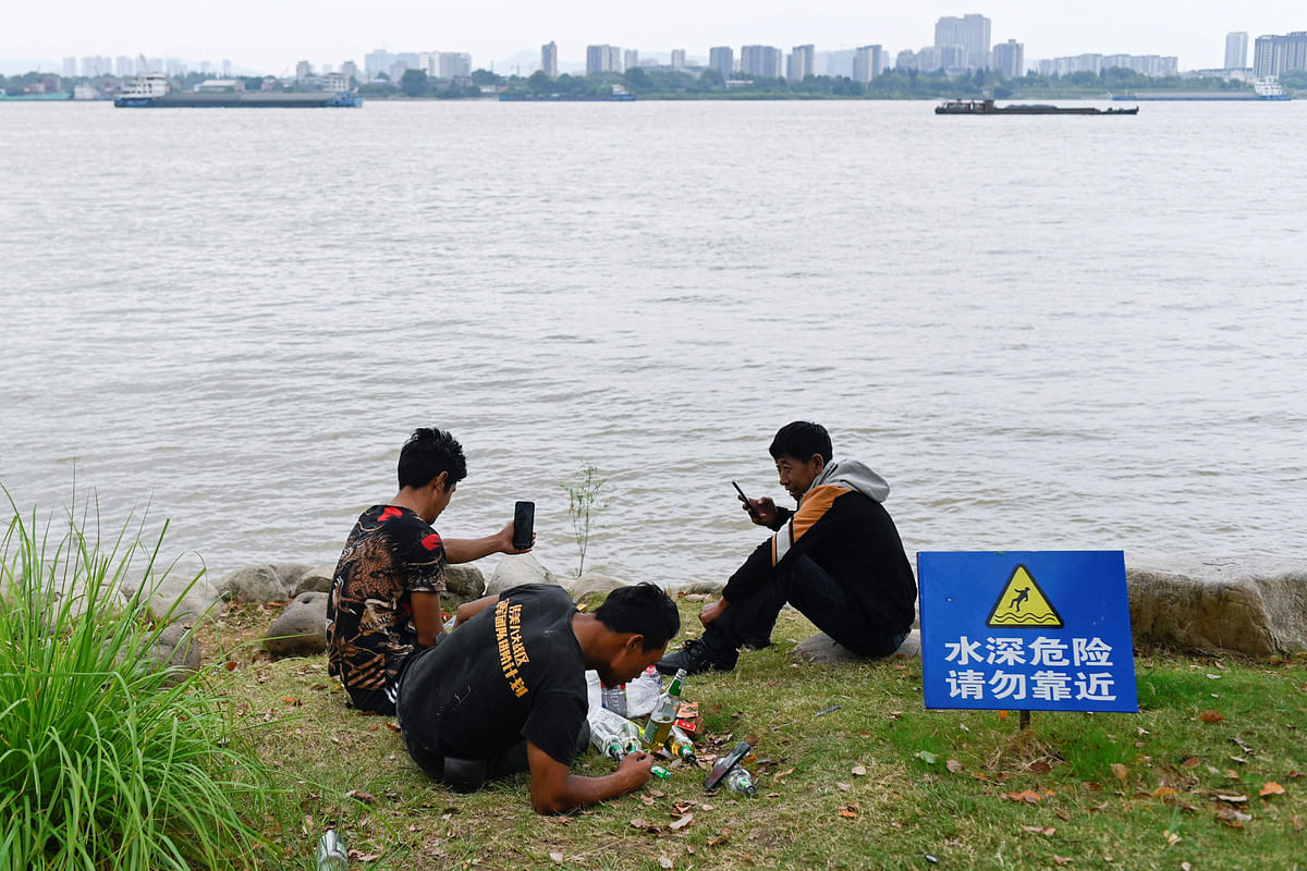 This picture taken on 2 September 2019 shows a group of men looking at their phones by the Yangtze River in Nanjing in China`s Jiangsu province. Photo: AFP