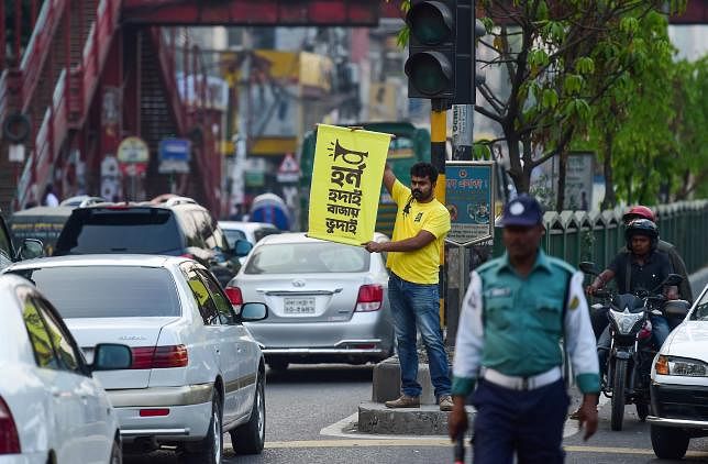 In this photo taken on 22 March 2019, Mominur Rahman Royal holds a banner with a Bengali slogan -- Horn hudai, Bajay Bhudai that translates to only the idiot honks horn unnecessarily -- on a busy street in Dhaka. Photo: AFP