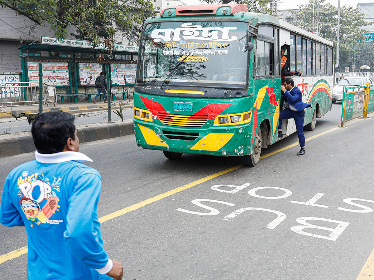 A man gets in a running bus in the middle of a road at Khilgaon, Dhaka on 11 January 2019. Photo: Dipu Malakar
