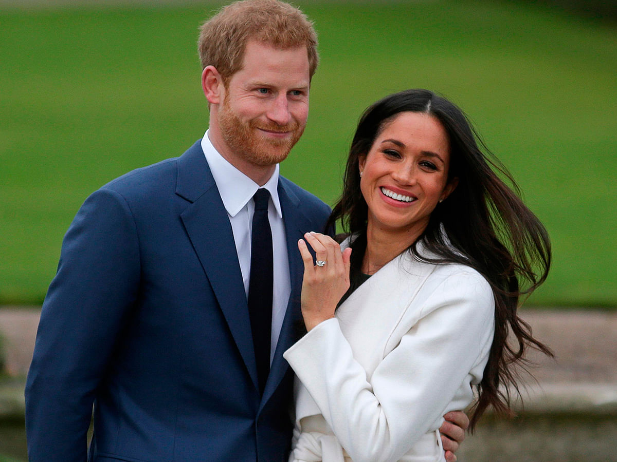 Britain`s prince Harry stands with his wife Meghan Markle. AFP File Photo