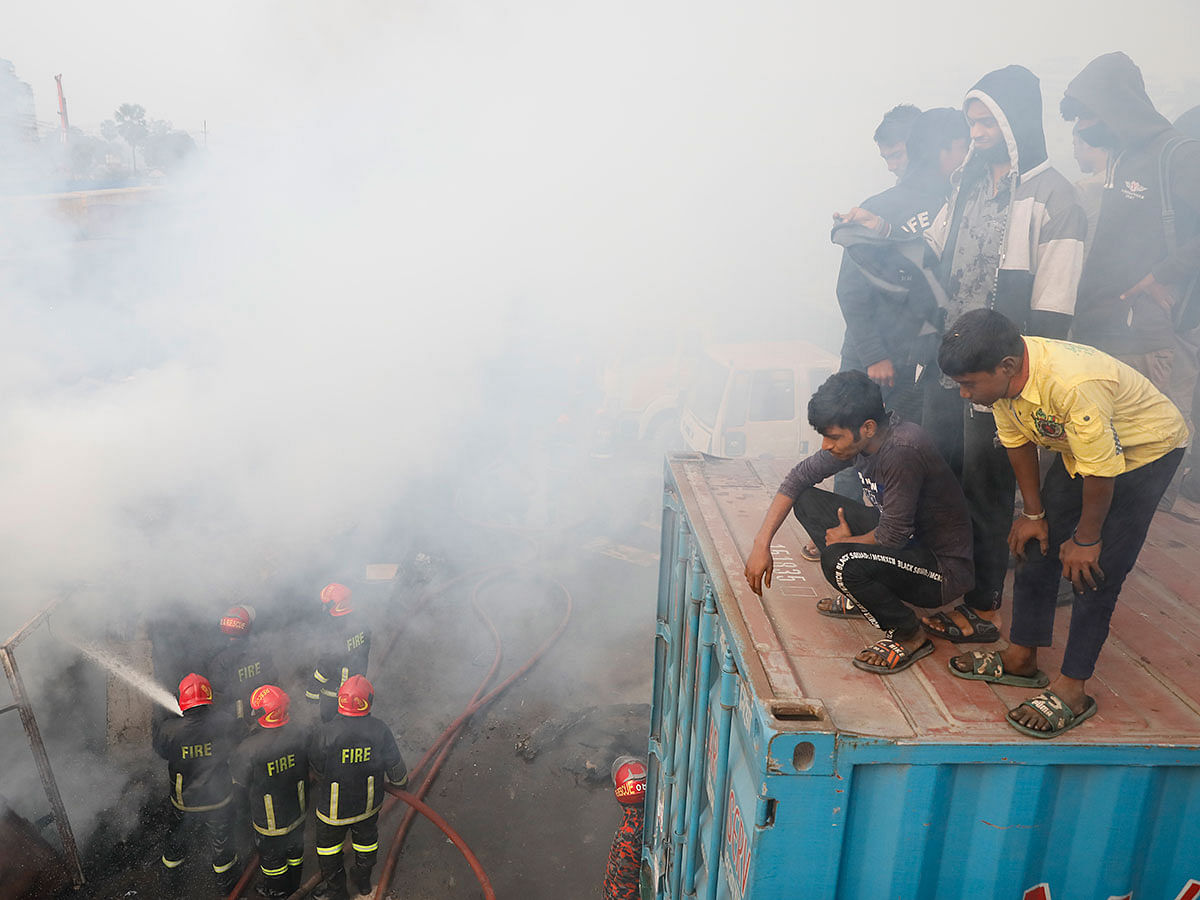 People watch fire service workers extinguishing fire at a makeshift set up inside an abandoned compartment at Tejgaon railway station, Dhaka on 12 January 2019. Photo: Ashraful Alam